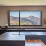 Vue panoramique intérieure d'un châssis fixe avec un ouvrant oscillo-battant en aluminium gamme Simple dormant visible, intégré dans une maison neuve à Itxassou