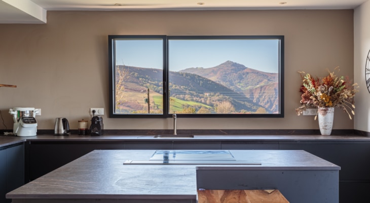 Vue panoramique intérieure d'un châssis fixe avec un ouvrant oscillo-battant en aluminium gamme Simple dormant visible, intégré dans une maison neuve à Itxassou